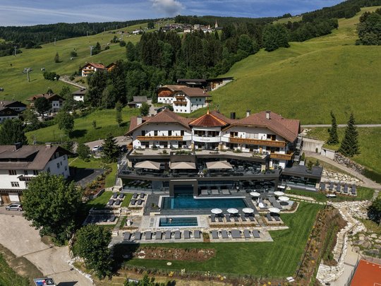 Hotel + Plan de Corones + Olang = mountain biking, climbing, tennis Hotel with outdoor pool and sun loungers in green mountain landscape on a sunny day