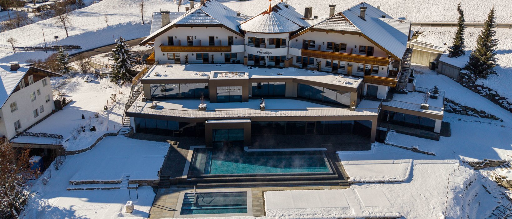 Wellnesshotel am Kronplatz: das Christoph-Erlebnis Verschneites Hotel mit beheiztem Außenpool in den Bergen