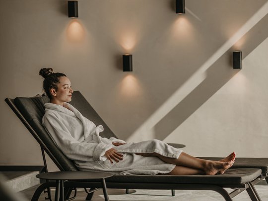 Hotel al Plan de Corones con spa: vacanza à la Christoph Donna in accappatoio bianco rilassata su lettino in ambiente spa elegante