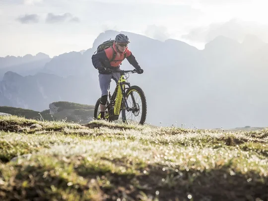 Hotel + Plan de Corones + Olang = mountain biking, climbing, tennis Man riding mountain bike in the mountains under cloudy sky