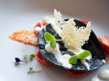 Hotel al Plan de Corones con spa: vacanza à la Christoph Ravioli neri con salsa bianca, foglie verdi e pomodorini come decorazione