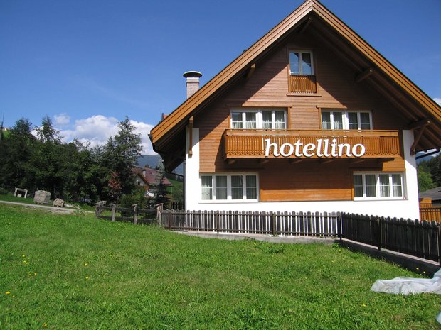 Die vier Häuser unserer Unterkunft im Pustertal Holzhaus mit Balkon und Beschilderung Hotellino bei sonnigem Wetter