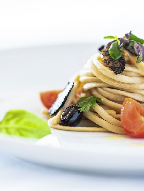 Wellness hotel at Plan de Corones/Kronplatz: the Christoph experience Garnished spaghetti with black olives, tomatoes, and fresh herbs on white plate
