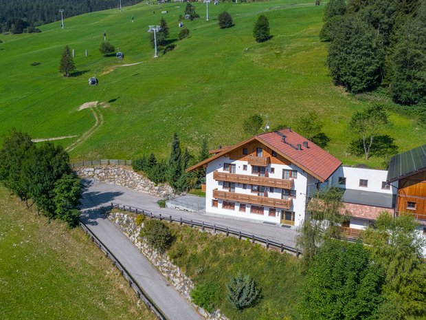 Die vier Häuser unserer Unterkunft im Pustertal Haus an einem grünen Berghang mit Seilbahn und Wald