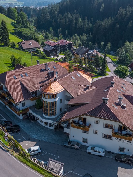 4-Sterne-Hotel am Kronplatz: Ihr perfektes Urlaubszuhause Luftaufnahme eines Hotels in einer bergigen Landschaft mit grünen Wiesen und Wäldern