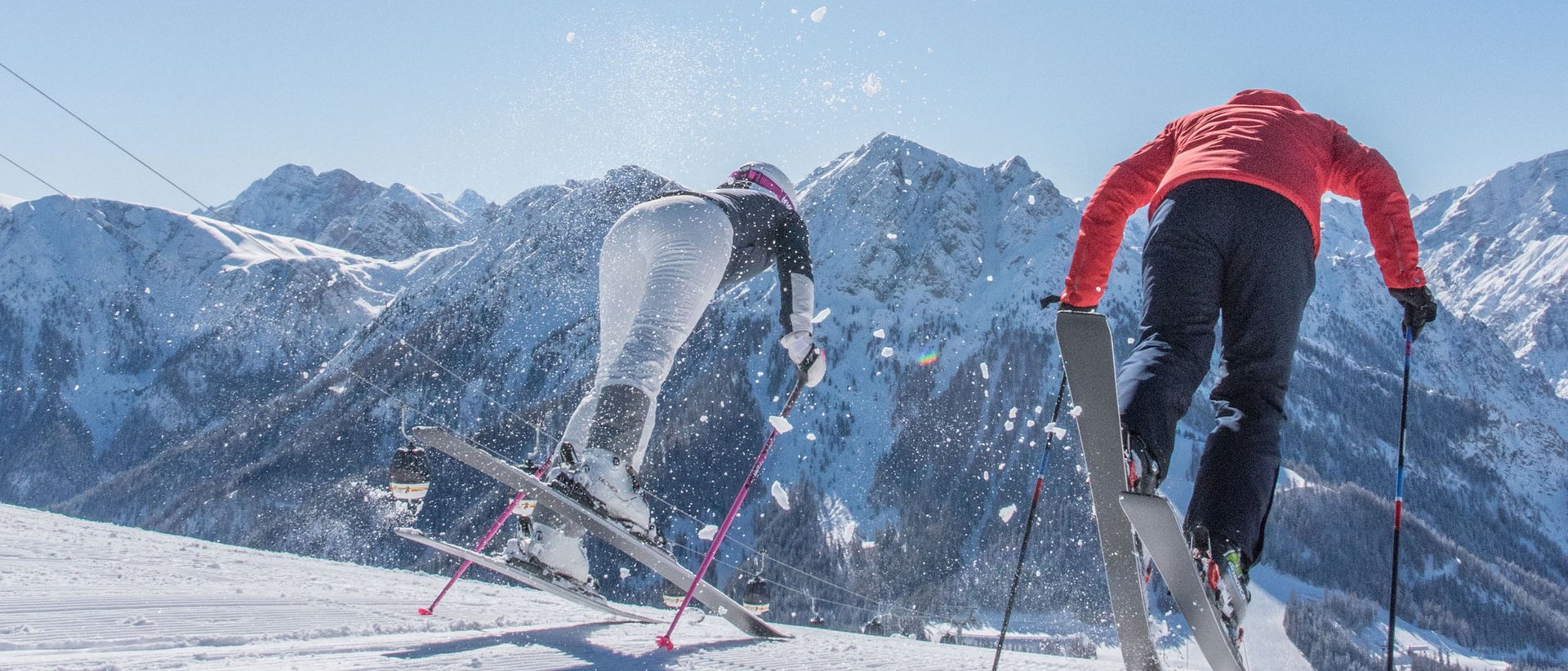 La stagione sciistica è iniziata! Due sciatori scendono una pista innevata sotto il sole tra le montagne