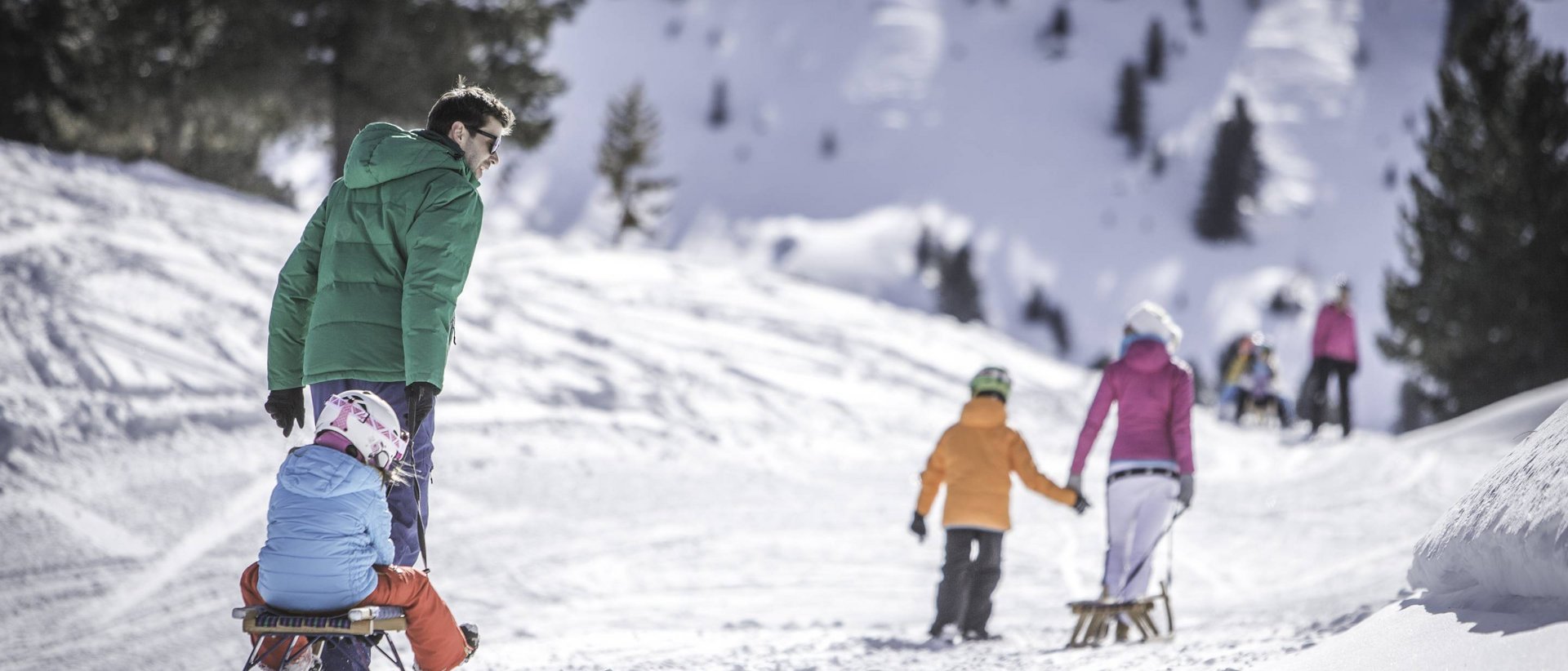 Slittino: divertimento per tutta la famiglia Famiglia sulla slitta nella foresta innevata in montagna