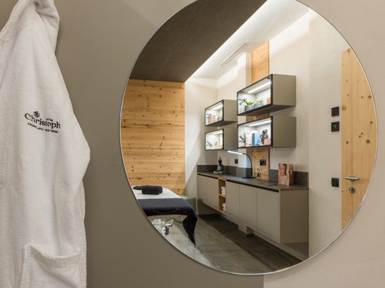 Hotel al Plan de Corones con spa: vacanza à la Christoph Accappatoio bianco appeso vicino a uno specchio rotondo con vista sulla stanza spa