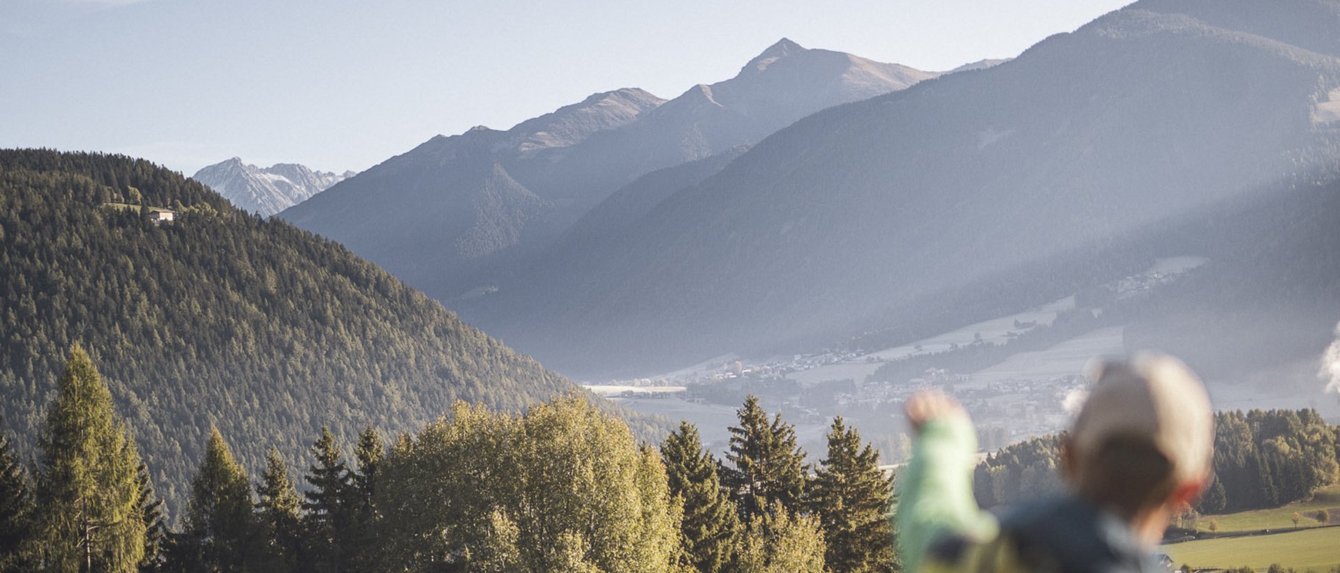 Outdoor-Aktivitäten im Frühling Wanderer zeigt auf bewaldete Berge und Tal bei klarem Himmel