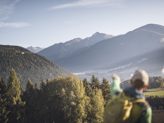 Novità dal nostro hotel al Plan de Corones Escursionista indica montagne boschive e valle sotto cielo limpido