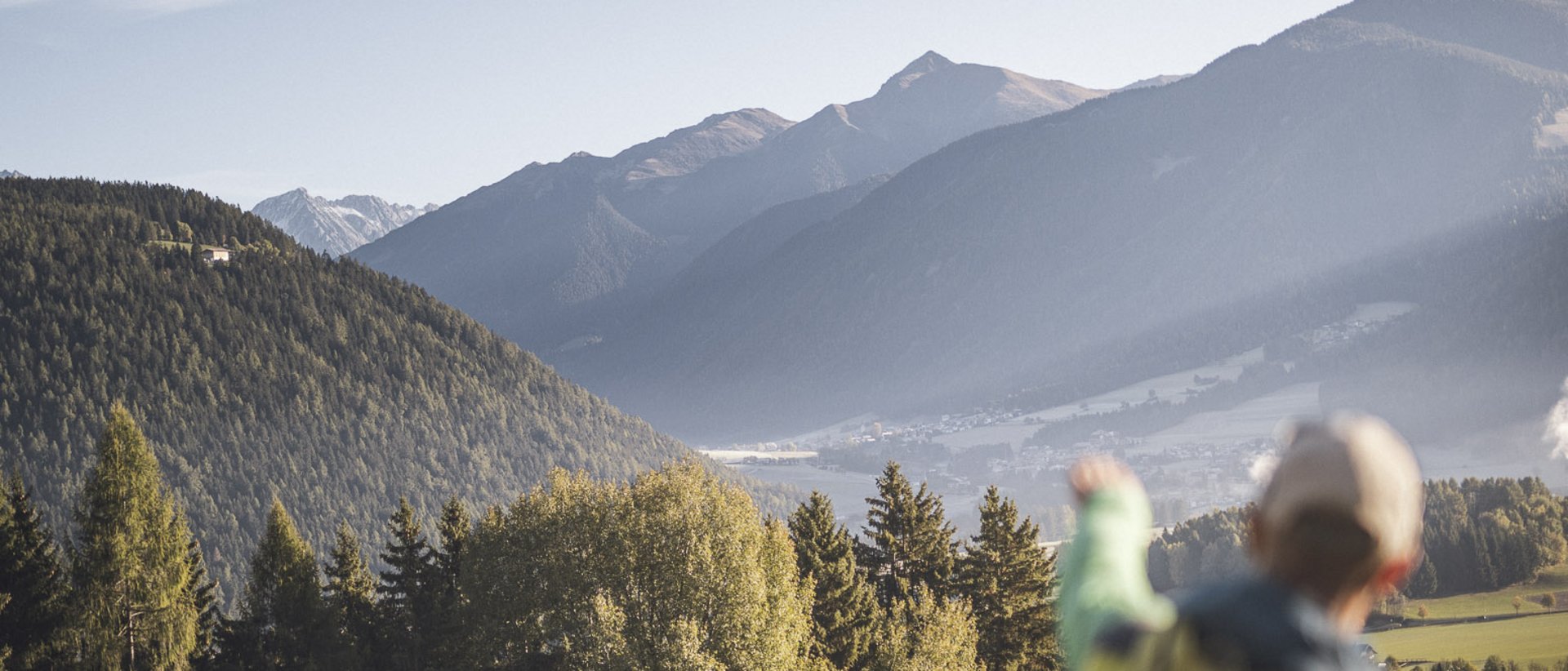 Attività all’aria aperta in primavera Escursionista indica montagne boschive e valle sotto cielo limpido