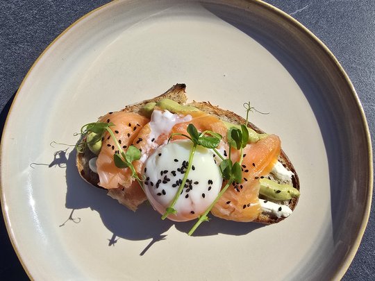 Concedetevi una pausa Toast con salmone, uovo in camicia, avocado e germogli su un piatto