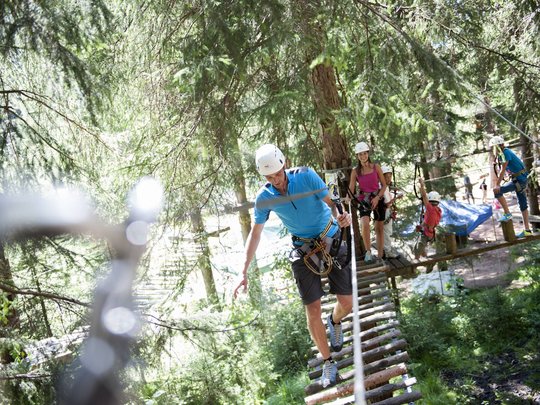 Hotel + Plan de Corones + Olang = mountain biking, climbing, tennis People climbing in a forest ropes course wearing helmets and safety harnesses