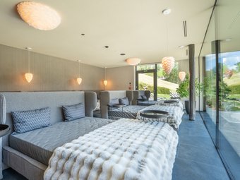 Hotel al Plan de Corones con spa: vacanza à la Christoph Lettini moderni con coperte e cuscini in una stanza benessere luminosa con parete in vetro
