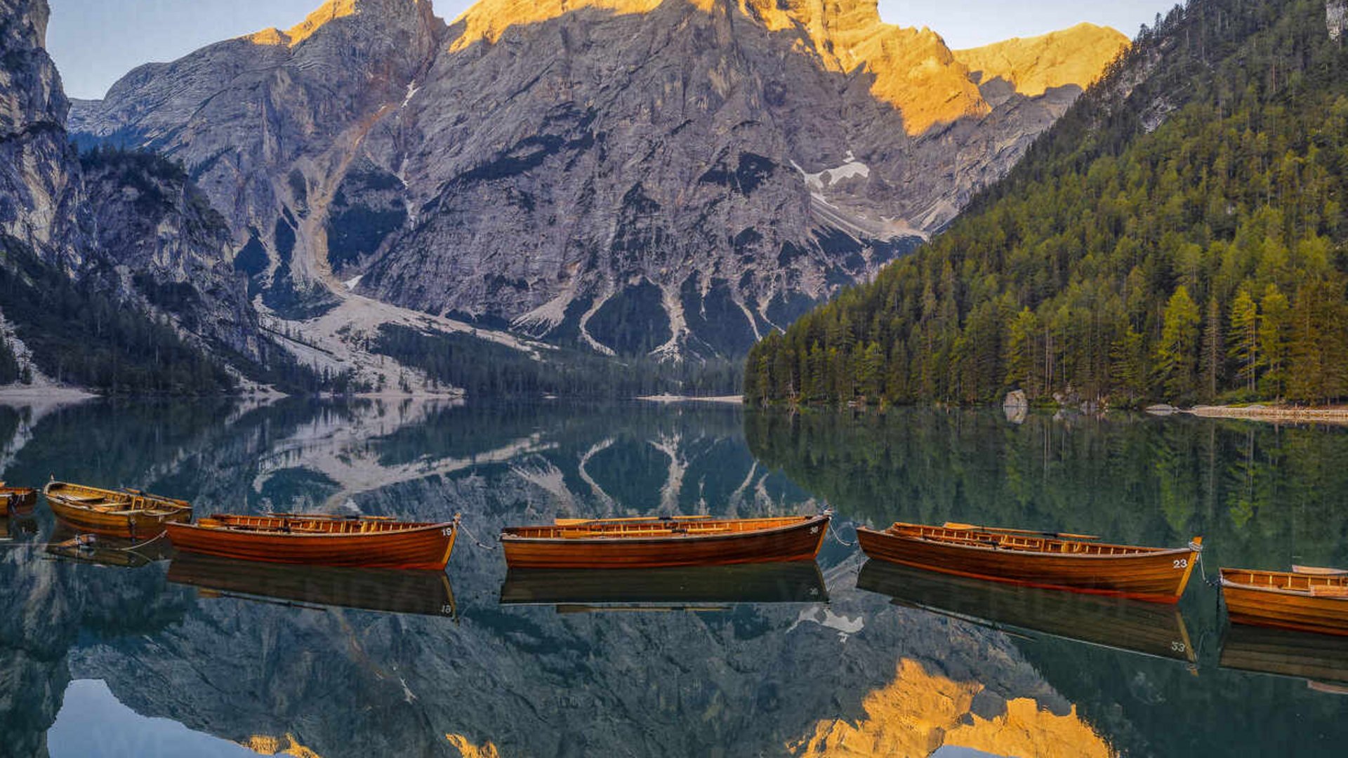 Uno dei gioielli delle Dolomiti a due passi dal Christoph Barche di legno su lago calmo con montagne al tramonto