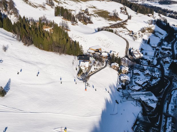 Sustainable 4-star hotel in the Dolomites Aerial view of a snowy ski area with chairlift and houses
