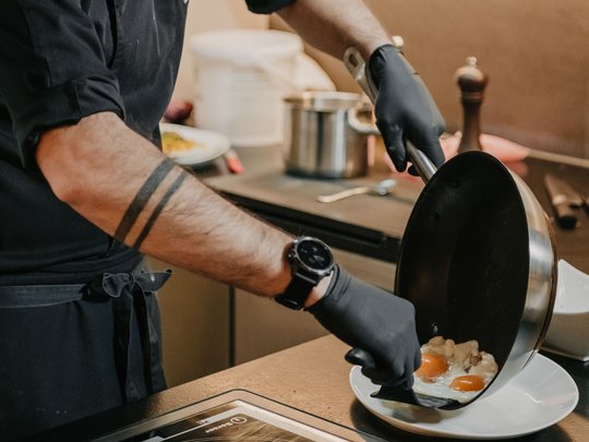 Concedetevi una pausa Cuoco versa uova fritte da padella su piatto in cucina moderna
