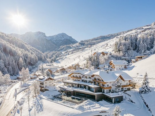 Willkommen in Olang: Hotel Christoph Schneebedeckte Berghütten und Bäume unter klarem, sonnigem Himmel