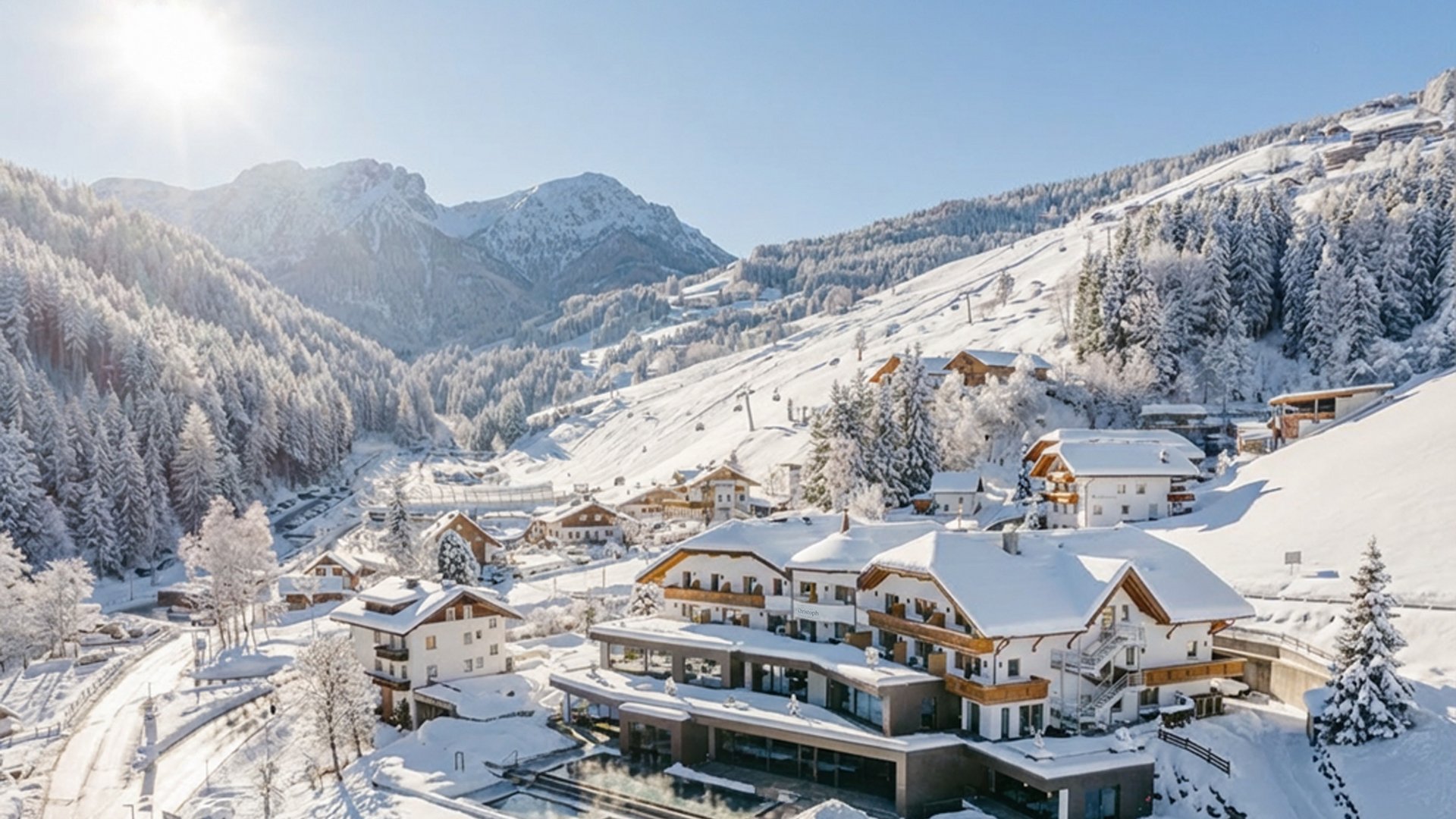 The four buildings of our accommodation in Val Pusteria/Pustertal Snow-covered mountain lodges and trees under clear sunny sky