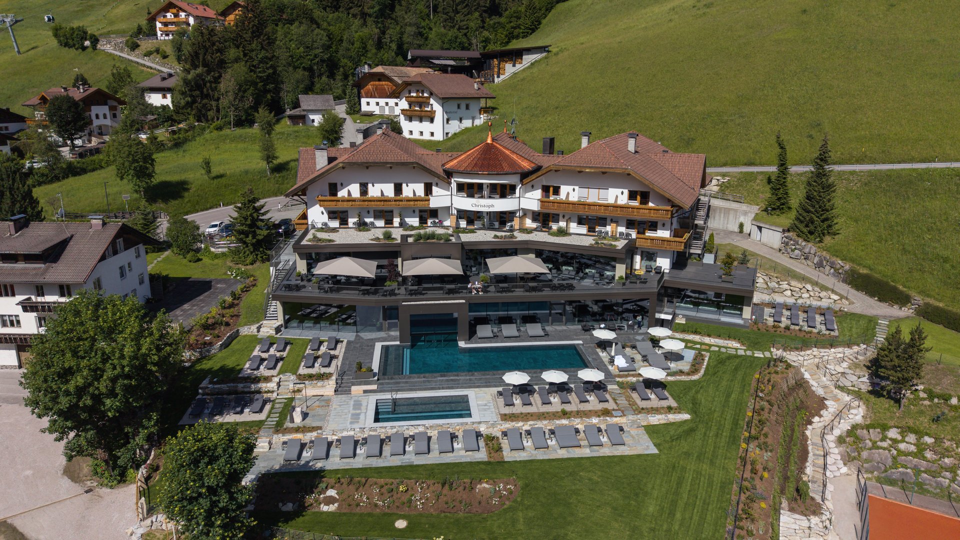 Concedetevi una pausa Veduta aerea di un hotel con piscina esterna e lettini in un paesaggio montano verde