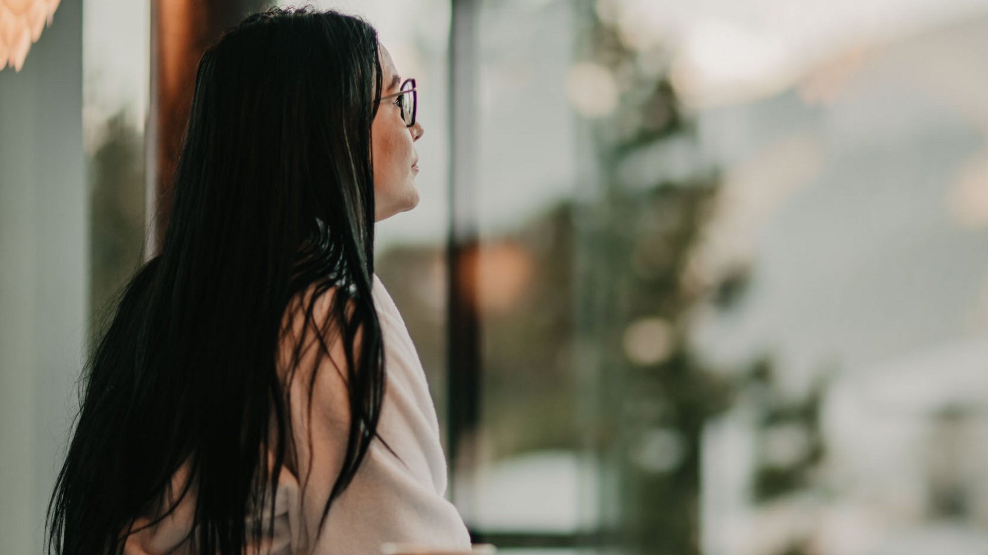 Una giornata di relax Donna in accappatoio seduta sul letto guarda fuori dalla grande finestra
