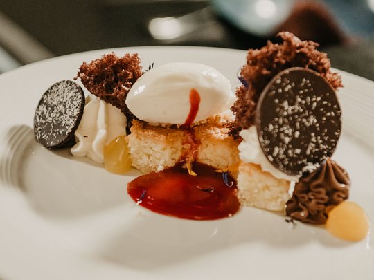 Concedetevi una pausa Dessert artistico con gelato, cioccolato e salsa di frutta su piatto bianco