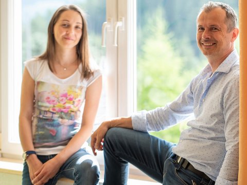 Hotel Christoph:immergetevi in in’atmosfera di benessere! Due persone sorridenti sedute vicino a una finestra con tende sullo sfondo