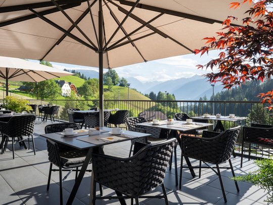 Le novità del nostro hotel a 4 stelle tra le Dolomiti Terrazza con tavoli, sedie e ombrelloni con vista sulle montagne