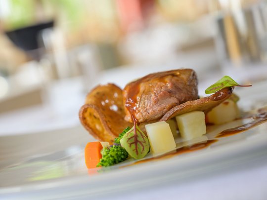 Regionale, alpine Küche im Hotel am Kronplatz in Südtirol Gourmetgericht mit zartem Fleisch, Gemüse und Sauce auf weißem Teller