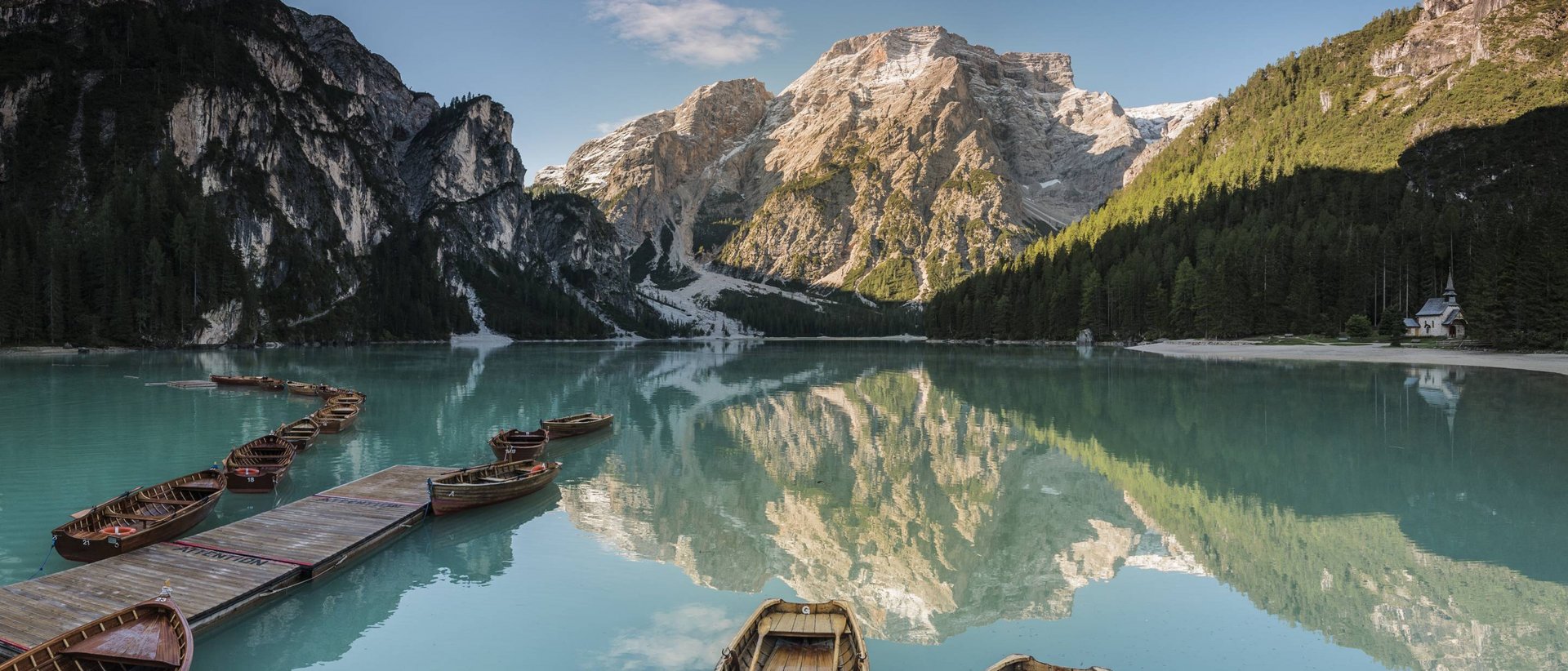Herbstliche Fotospots im Pustertal Holzboote auf ruhigem Bergsee mit Spiegelung und bewaldeten Bergen