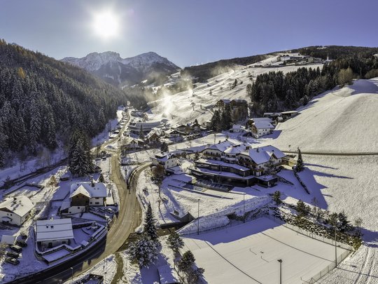 Unforgettable skiing holiday on Plan de Corones/Kronplatz Snow-covered village in sunny valley with forested mountains