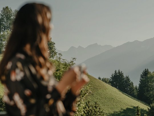 Concedetevi una pausa Donna con tazza sul balcone guarda colline verdi e montagne sotto cielo limpido