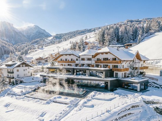 A warm welcome to our hotel in Olang, at Plan de Corones/Kronplatz Hotel with heated outdoor pool in snowy mountain landscape on a sunny winter day