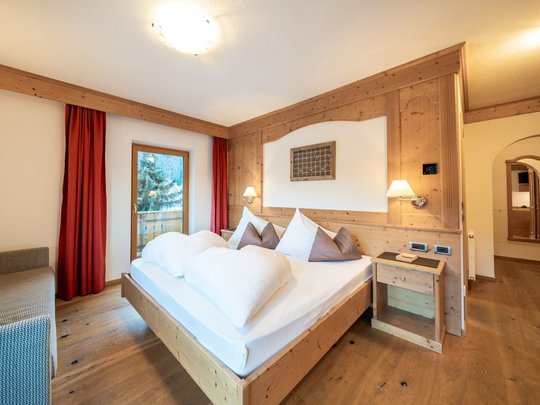 Novità dal nostro hotel al Plan de Corones Camera d'albergo accogliente con mobili in legno e letto matrimoniale