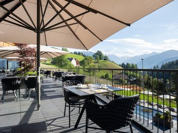 Le novità del nostro hotel a 4 stelle tra le Dolomiti Terrazza con tavoli, sedie e ombrelloni con vista sulle montagne