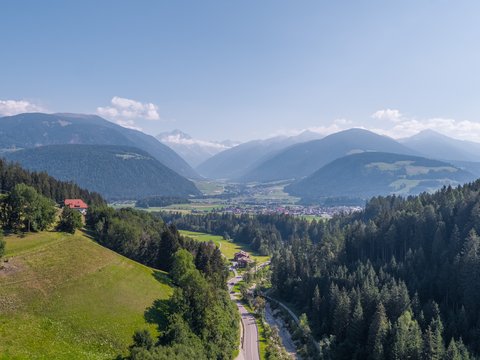 Vorbei am Pragser Wildsee zum Hotel: Ihr Weg in den Urlaub Berglandschaft mit Tal, Wald und Straße unter klarem Himmel