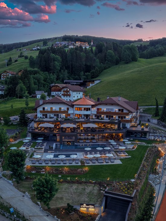 Willkommen in Olang: Hotel Christoph Hotel Christoph bei Abenddämmerung in grüner Berglandschaft mit Tennisplatz