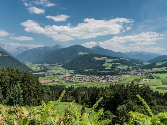 Hotel a Valdaora: vi diamo un caloroso benvenuto! Veduta di una valle con villaggi, montagne e foreste sotto cielo azzurro