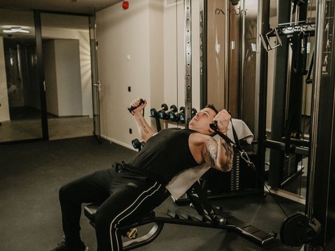 A swim in Lago di Braies? A hotel with a pool? Let’s go for a dip! Man working out chest muscles on incline cable machine at gym.