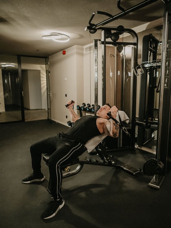 Hotel al Plan de Corones con spa: vacanza à la Christoph Uomo che si allena con macchina a cavi inclinata in palestra.