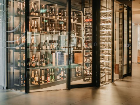 Active wellness holiday in Val Pusteria/Pustertal with the Lanz family Modern wine cellar with glass walls and lit shelves full of wine bottles