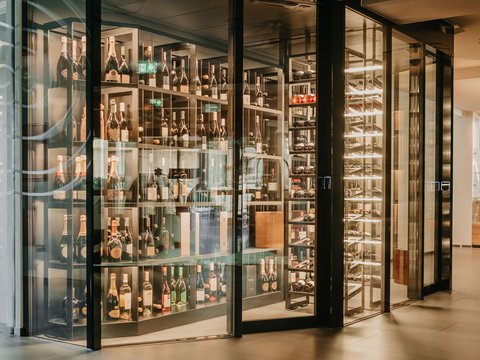 Active wellness holiday in Val Pusteria/Pustertal with the Lanz family Modern wine cellar with glass walls and lit shelves full of wine bottles