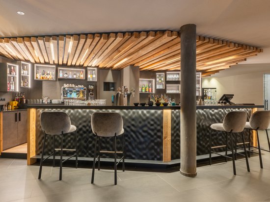 Apartment A Modern hotel bar area with illuminated wood design and tall bar stools