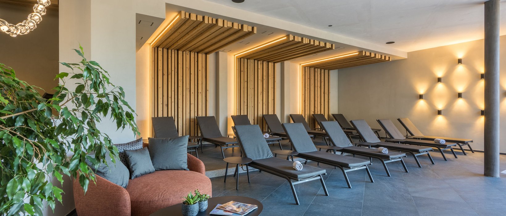 Eines der schönsten Hotels in den Dolomiten für Wintergenuss Moderner Ruheraum mit Liegen, Holzverkleidung und stimmungsvoller Beleuchtung