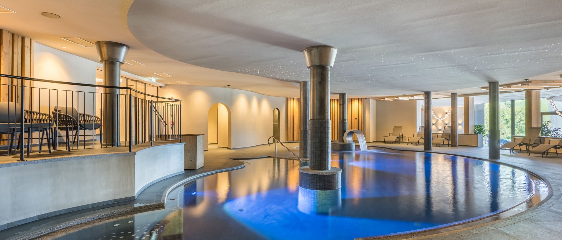 Attività per giornate uggiose Piscina coperta moderna con acqua illuminata e lettini