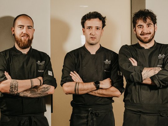 Concedetevi una pausa Tre cuochi in divisa nera con le braccia incrociate in una cucina