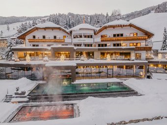 Wellnesshotel am Kronplatz: das Christoph-Erlebnis Hotel Christoph im Winter mit beleuchtetem Außenpool und Schnee