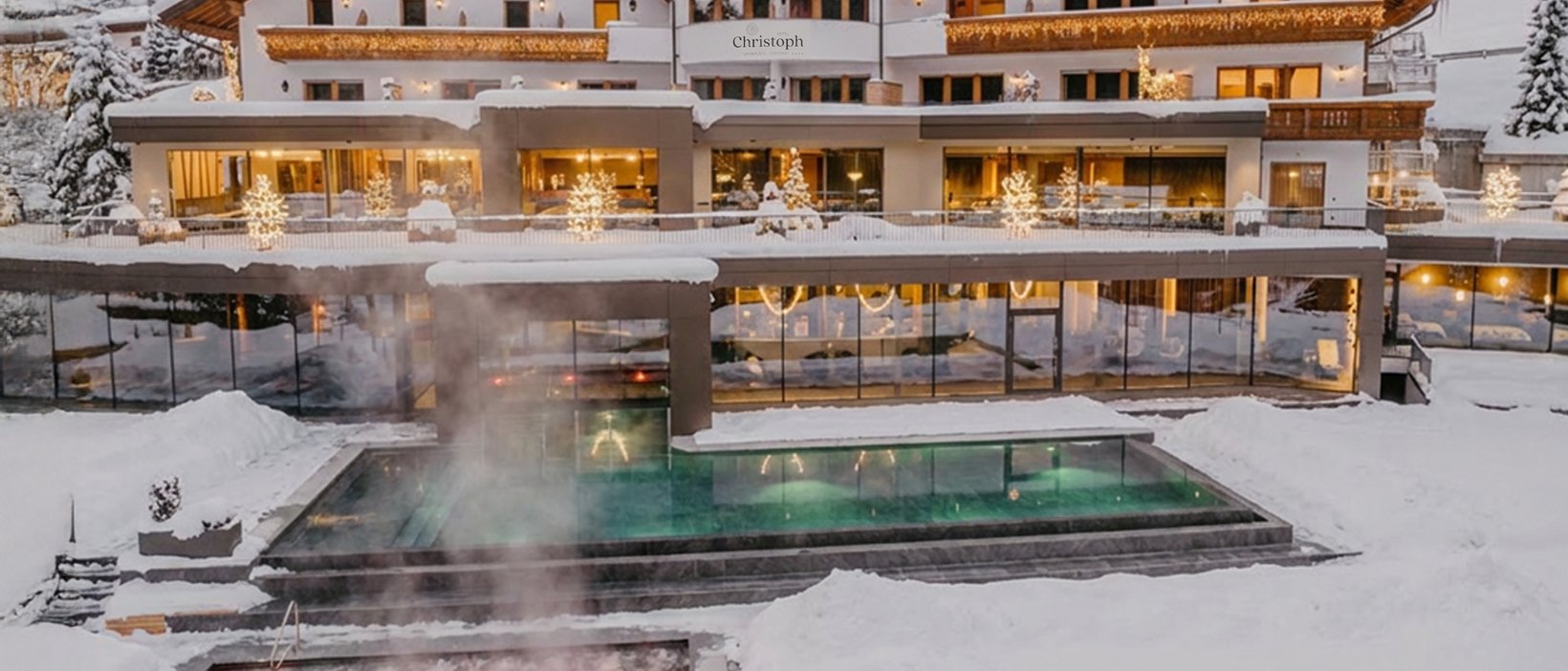 Wellnesshotel am Kronplatz: das Christoph-Erlebnis Hotel Christoph im Winter mit beleuchtetem Außenpool und Schnee