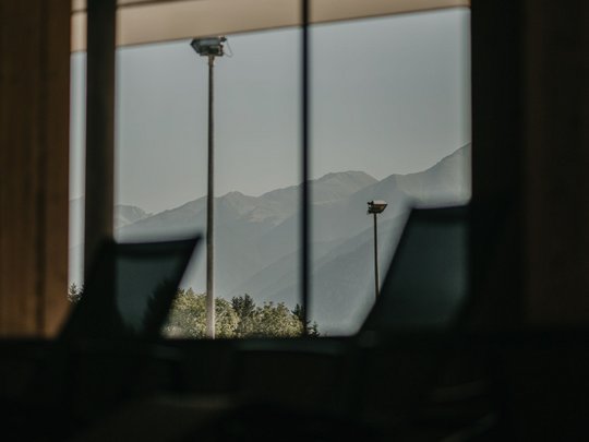 Novità dal nostro hotel al Plan de Corones Vista sulle montagne da una finestra ampia in una stanza scura con sedie