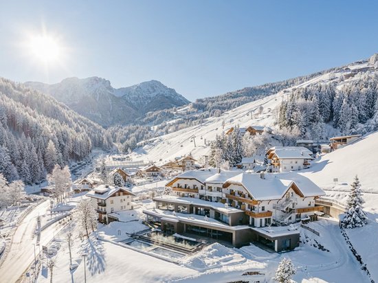 A warm welcome to our hotel in Olang, at Plan de Corones/Kronplatz Snow-covered village in the mountains on a sunny winter day